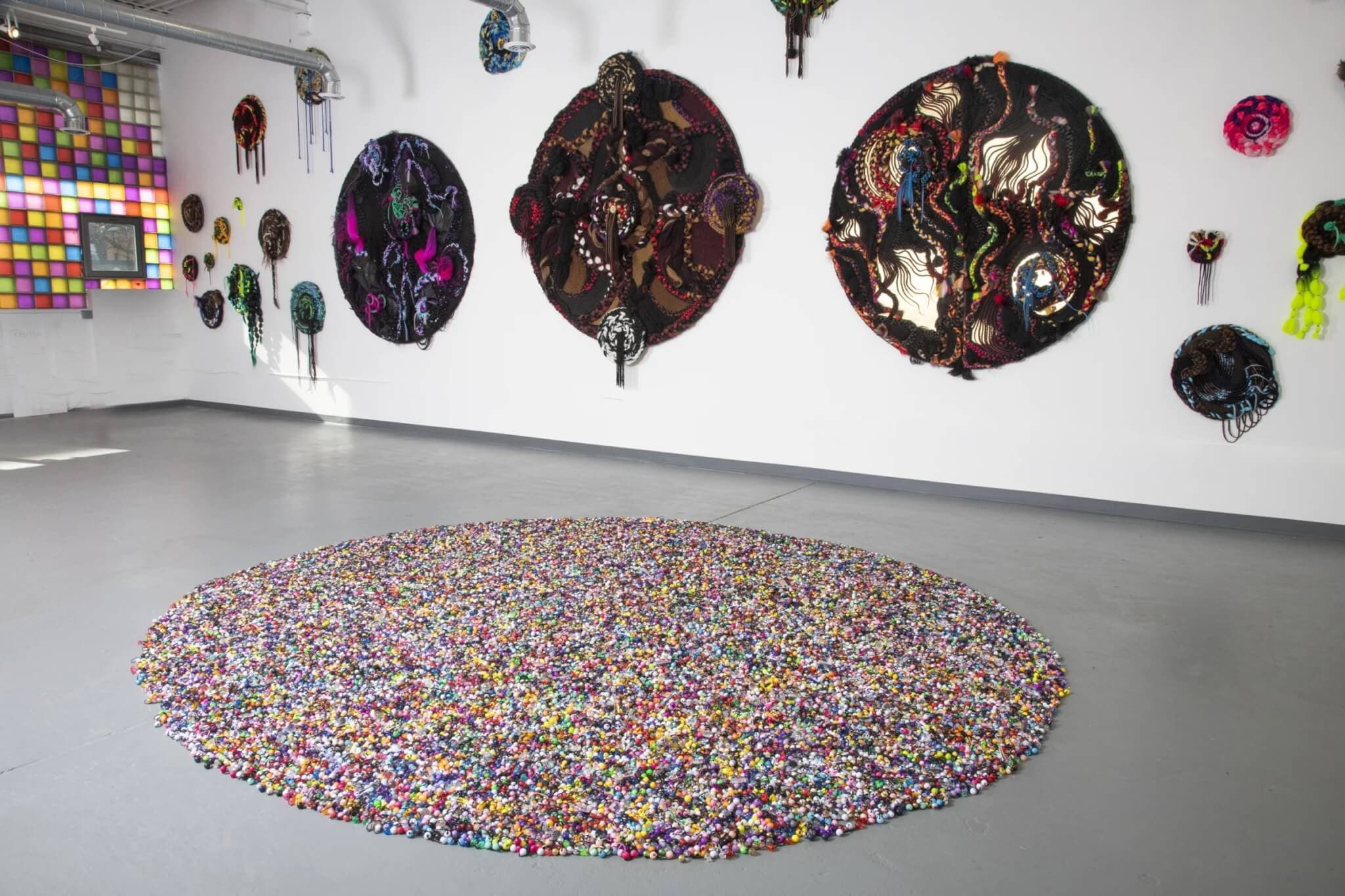 Colorful artwork by Nafis M. White adorns the walls and floor of a space at Central Contemporary Arts.