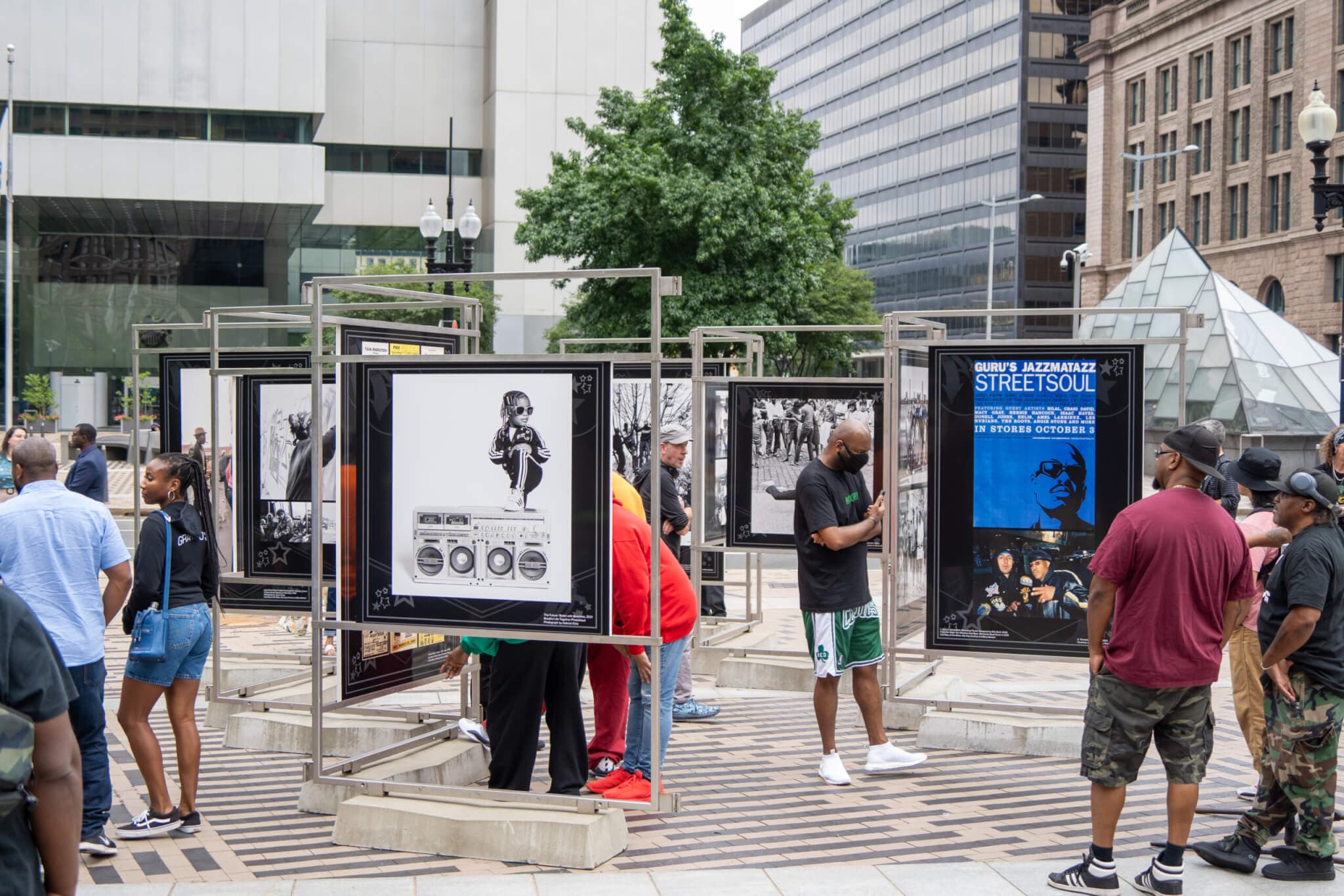 Outside at The Greenway, visitors mingle and view panels that comprise an installation.